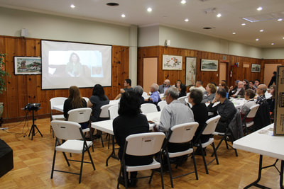 Crowd watches video at Pacific Atrocities Education Summer Showcase and Fundraiser event