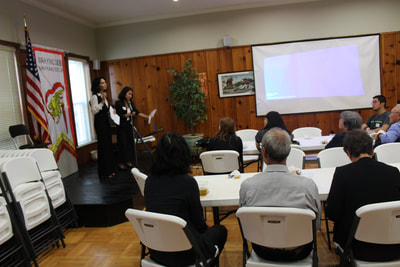 Two individuals present a PowerPoint at Pacific Atrocities Education Summer Showcase and Fundraiser event